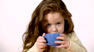 A six-year-old sweet girl just drank tomato juice. The lips of a playful girl are soiled with tomato juice. On the face of the child a happy smile