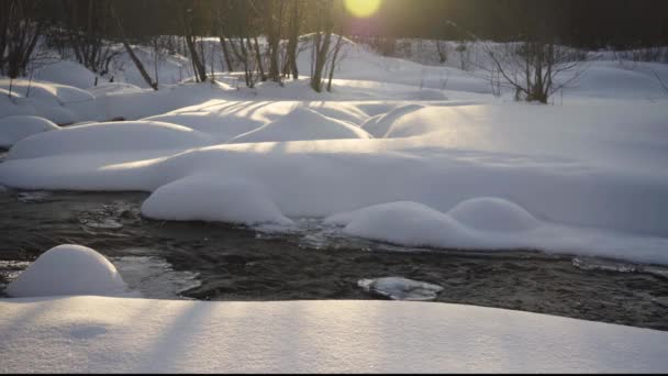 Sneeuwvlokken Oevers Van Een Bosrivier Stralen Van Rijzende Zon — Stockvideo