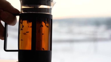 Sabah güneşinin altında şeffaf camdan yapılmış çaydanlık. Cam çaydanlıkta yüzen siyah çay parçacıkları, demlenmiş, makro..