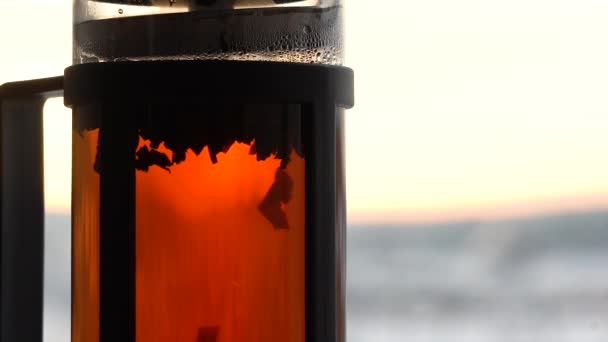 朝の日差しの下で透明なガラス製のティーポット ガラスのティーポットに浮かぶ紅茶の粒子 マクロ — ストック動画