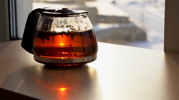 茶壶一种茶壶 由透明的玻璃杯在晨阳的照耀下制成在玻璃杯茶壶中漂浮的红茶粒 酿制而成 — 图库视频影像