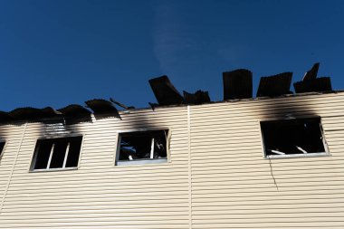 Yanmış bir duvar ve kırık camlı bir dükkan. Yangının sonuçları.