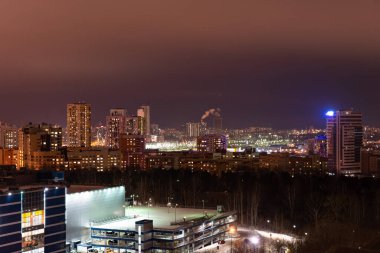 Kış gecelerinde yerleşim yerleri. Çok katlı binaların parlayan pencereleri. Bahçede bir sürü park edilmiş araba var..