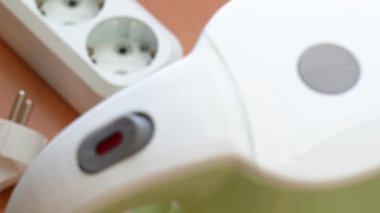 Elektrikli su ısıtıcısını aç. Güç kablosunu bağla. Elleri su ısıtıcısının düğmesini açmak için uzanır.