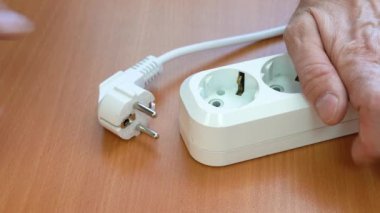 Güç kablosuna bağlan ve bağlantıyı kes. Bir erkek el bir elektrik kablosunu uzatma kablosuna bağlar. Bir uzatma kablosuna bağlı elektrik prizi.