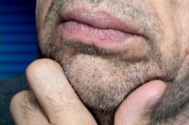 Çene kılları. Sakallı yaşlı bir adam eliyle tıraş olmamış yüzüne dokunur. Tıraşsız birkaç gün. Bir adamın yüzündeki kıllar, kısa bir sakal..