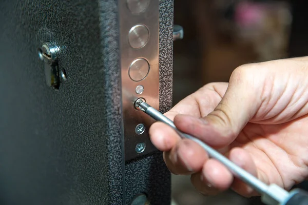 A man repairs a door lock. Close-up. selective focus