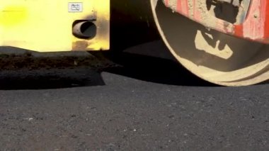 Çalışan bir buz pateni pistine yakın çekim. Sıcak asfalt. Askı tamiri. Tekerleğin büyük çalışma makinesi yeni asfalt yapar.