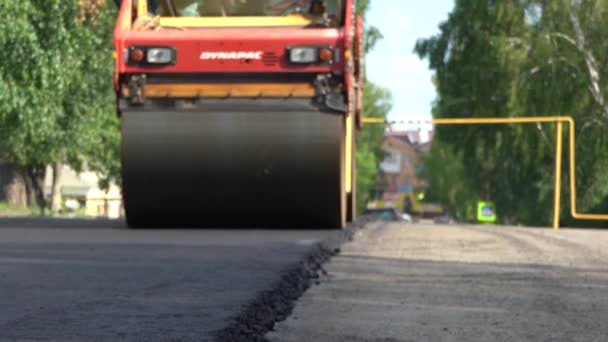 Jekatěrinburg, Rusko - červen2019. Rozmazaný obraz. Horký vzduch. Detailní záběr horkého asfaltu na fungujícím kluzišti. Oprava chodníku. Velký pracovní stroj válce vyrábí nový asfalt — Stock video