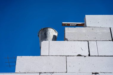 Köpük bloklardan bir duvar inşa et. Mavi gökyüzüne karşı yeni beyaz köpük blokları duvarı.