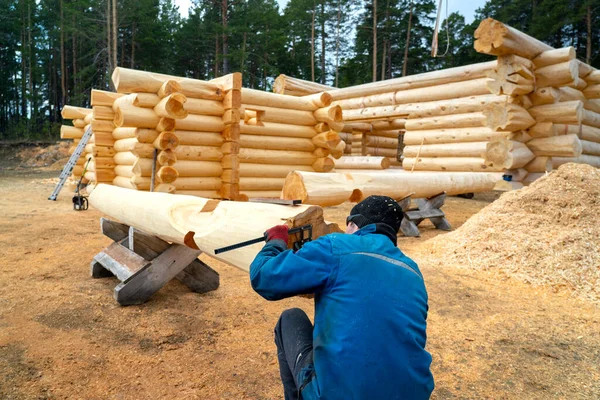 Build a house from logs. Preparation of logs for the assembly of the structure. Assembly of a wooden log house at a construction base.