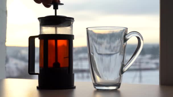 紅茶をグラスに注ぐ 冬の朝 外には窓から雪が見える グラスティーポットで紅茶 冬の朝を背景に — ストック動画