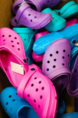 Yazlık plaj ayakkabıları satışı. Yaz soyut geçmişi. Birçok plastik renkli sandalet indirimde.