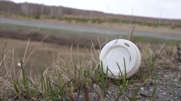 Műanyag hulladék az út szélén a fűben. Használt kávéscsésze. Szennyeződési probléma. — Stock videók