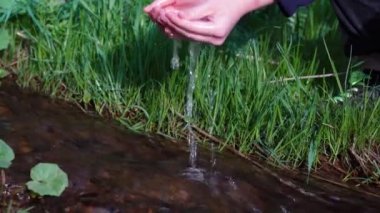 Kız sarhoş olmak için elleri temiz bir dağ deresinde su topluyor. Eller yukarı.