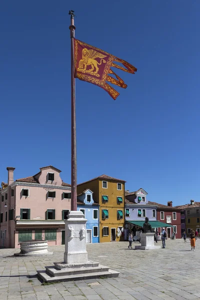 The Venetian flag on the island of Burano in the Venetian Lagoon, northern Italy. It is situated near Torcello at the northern end of the Lagoon, and is known for its lace work and brightly coloured homes.