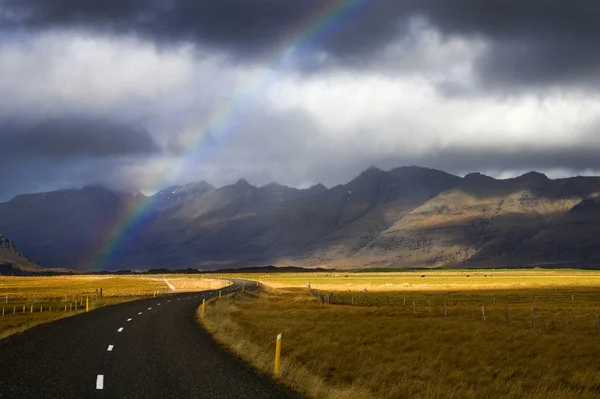 Rainbow over a rural road in the east of Iceland — Stock Photo, Image