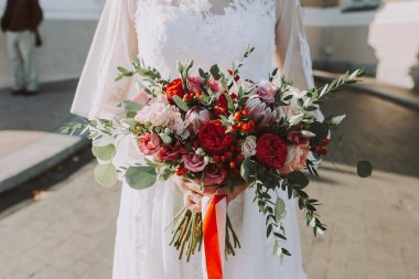 Düğünde, gelin ve damat birlikte güzel giysiler içinde düğün buketini ellerinde tutuyorlar.