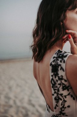 Bronzlaşmış bir esmer, arkası açık bir vücut elbisesi giyiyor. Güzel çizgiler sırtı büker. Kadının şehvetli ayrıntıları.