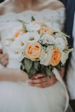 Düğün için. Gelin ve damat, ellerinde bir buketle, doğa bahçesindeki düğün töreninde ayakta duruyorlar..