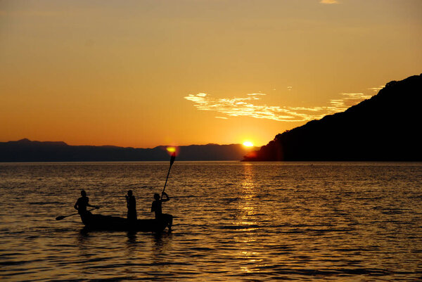 Men in a canoe at sunset on Lake Malawi