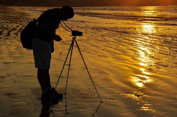 Un photographe sur la plage au coucher du soleil — Photo