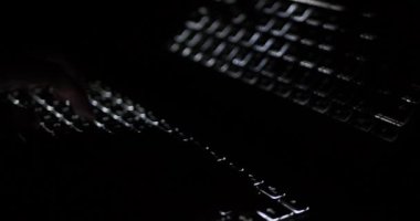 Karanlıkta parlayan dizüstü bilgisayarda yazan kişi