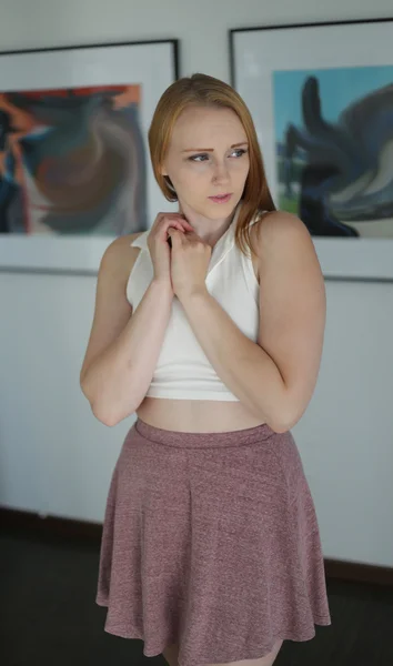 Red Haired Woman in White Top dans une galerie d'art (note : les peintures ont été modifiées numériquement et ne ressemblent pas à l'œuvre d'art originale. Aucune libération de propriété nécessaire ). — Photo