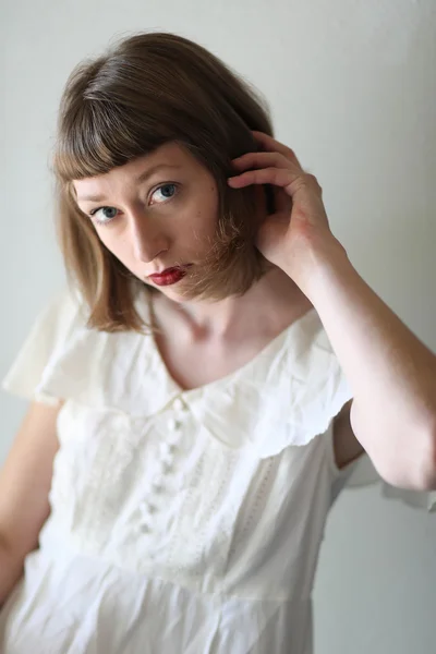 Mooie vrouw in een witte jurk in venster licht — Stockfoto