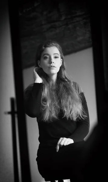 Hermosa mujer en vestido negro mirándose en un espejo —  Fotos de Stock