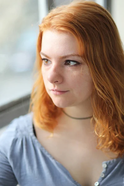 Rood harige vrouw in grijze knop ingedrukt boven — Stockfoto