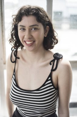 Siyah saçlı ve tabaklanmış deri kameraya bakarak ile çok çekici bir kadın. O bir siyah ve beyaz çizgili üst giyiyor.