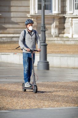 Madrid, İspanya - 22 Mayıs 2020: kendini covid-19 'dan korumak için maskeli elektrikli scooter kullanan adam