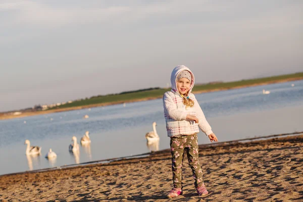 Glad liten tjej på en promenad vid sjön — Stockfoto