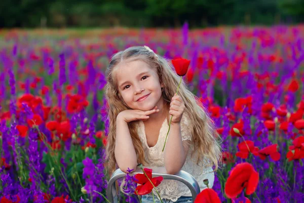 Gelukkig klein meisje op een gebied van papavers — Stockfoto