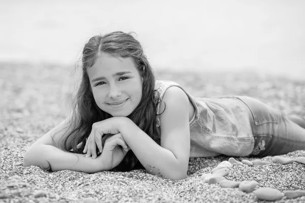 Glückliches kleines Mädchen am Strand liegend — Stockfoto