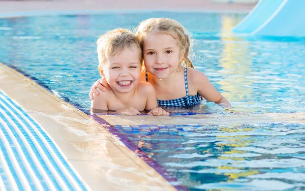Glada unga barn i poolen kramas — Stockfoto