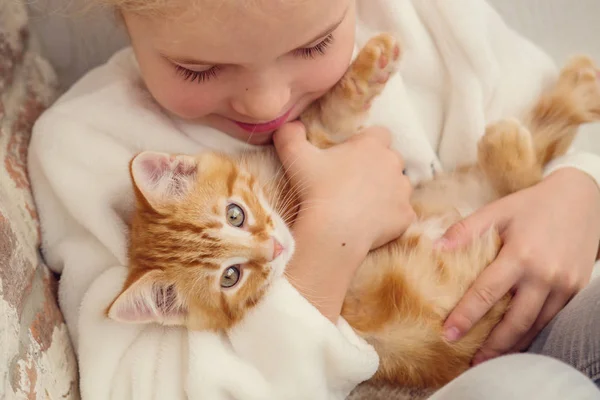 Linda niña sosteniendo un gatito en una mano de jengibre — Foto de Stock
