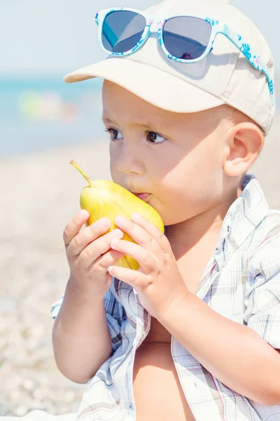 Toddler boy eating a pear in the summer — Stock Photo, Image