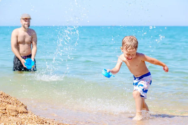 Happy father splashing water on laughing son — Stock Photo, Image