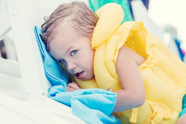 Słodkie małe dziecko w nadmuchiwane kamizelki, leżąc na leżaku — Zdjęcie stockowe