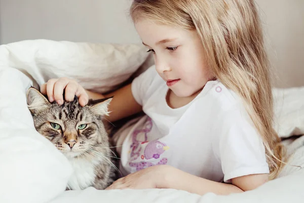 Charmantes kleines Mädchen umarmt ihre Katze liegend — Stockfoto