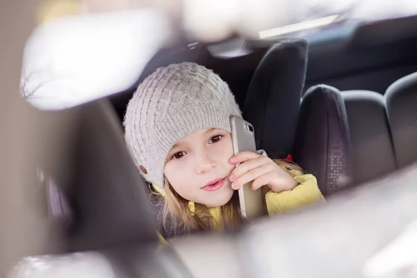 Enfant assis sur le siège arrière et jouer avec un téléphone mobile — Photo