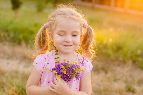 Schönes kleines Mädchen pflückt Blumen auf einer Wiese — Stockfoto