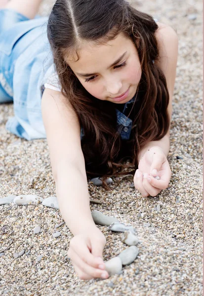 Dívka si hraje s kameny ležící na oblázky — Stock fotografie