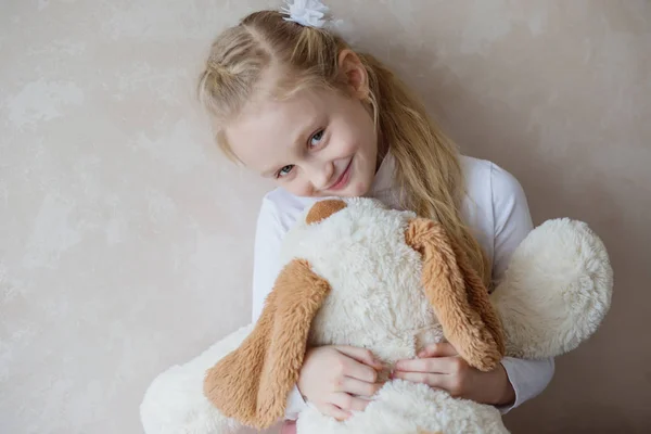 Leende liten flicka som håller en leksak hund — Stockfoto