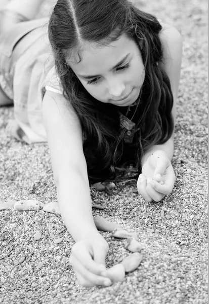 Chica jugando con piedras tumbadas en las piedras —  Fotos de Stock