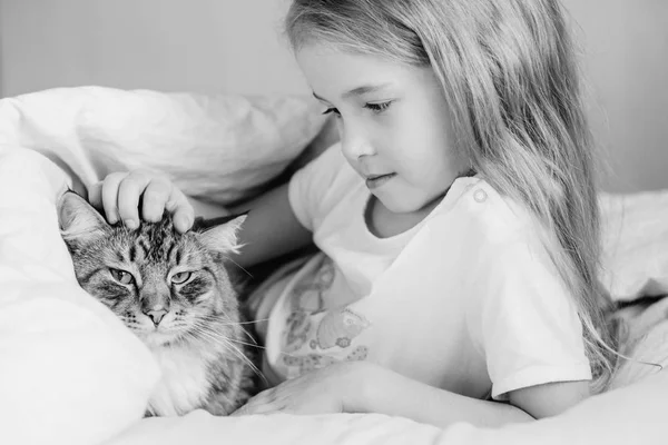 Encantadora niña abrazando a su gato acostado — Foto de Stock