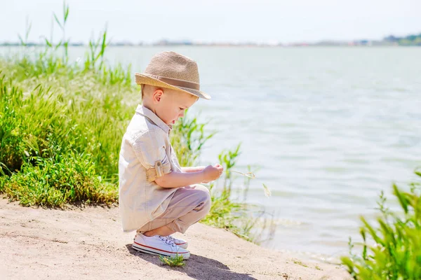 Маленький мальчик сидит на озере и играет — стоковое фото
