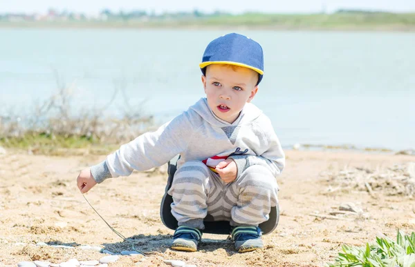 Little boy is sitting on the shore of the lake — Stock Photo, Image